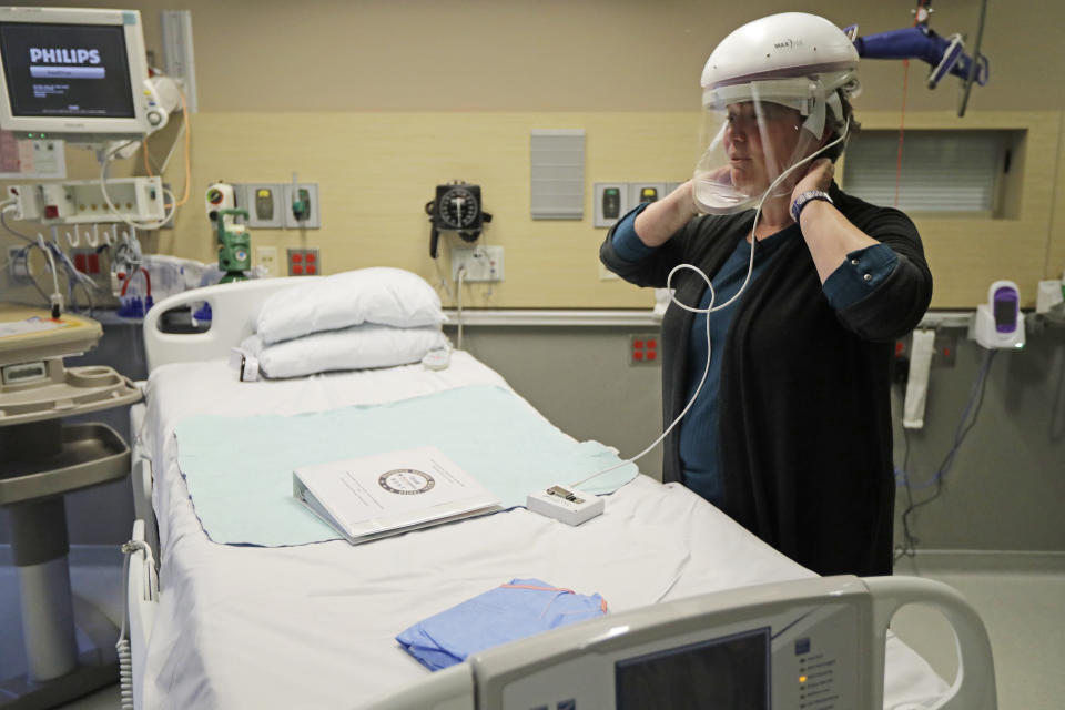 In this Thursday, Jan. 23, 2020 photo, Robin Addison, a nurse at Providence Regional Medical Center in Everett, Wash., demonstrates how she wears a respirator helmet with a face shield. It is similar to the one she used when she helped treat a man, currently in isolation at the hospital, who is believed to be the first person in the U.S. to have contacted a dangerous new virus that originated in China. (AP Photo/Ted S. Warren)