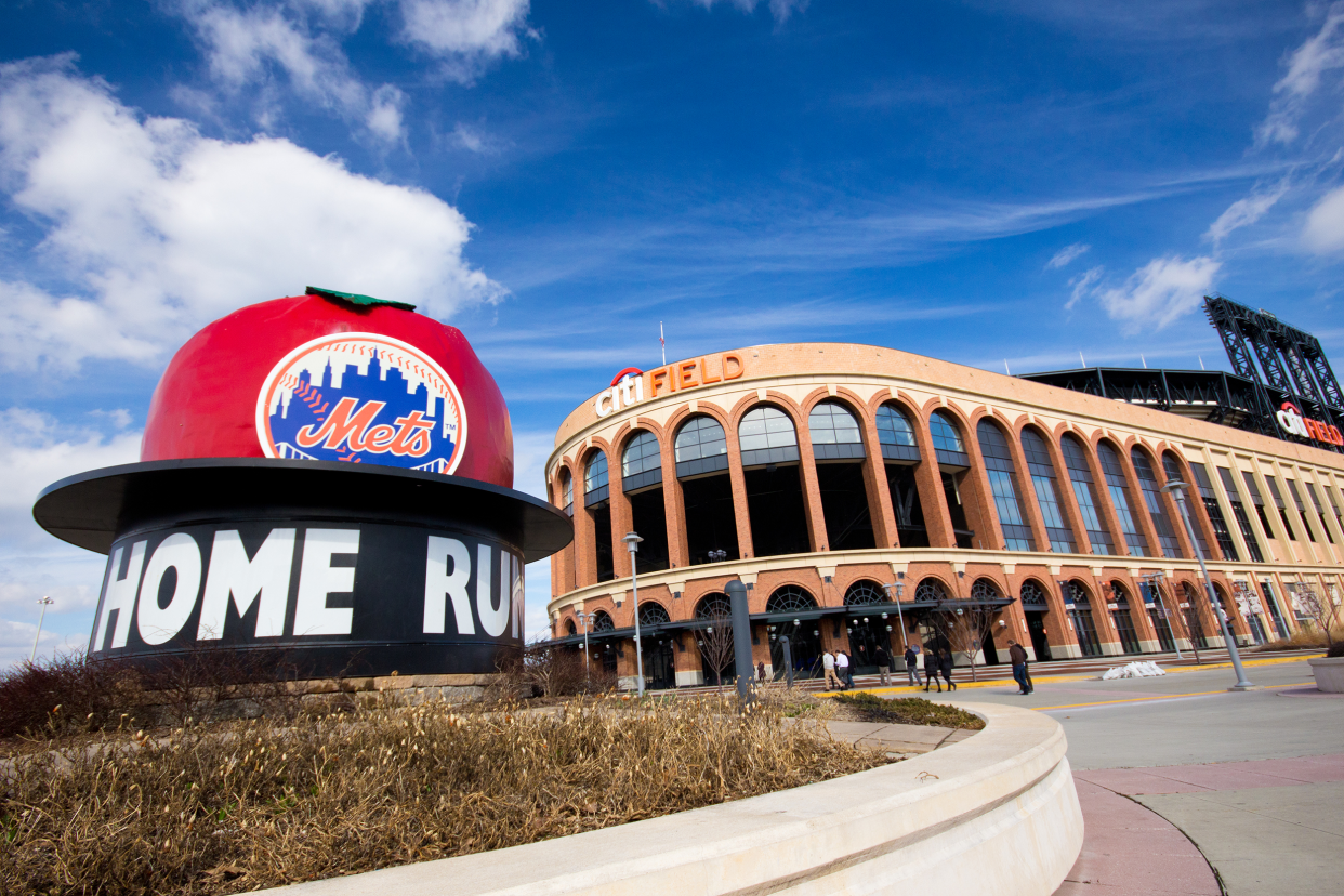 Exterior of Citi Field, Queens, New York, home of the New York Mets as seen from the Home Run Apple outside with a bright blue sky in the background