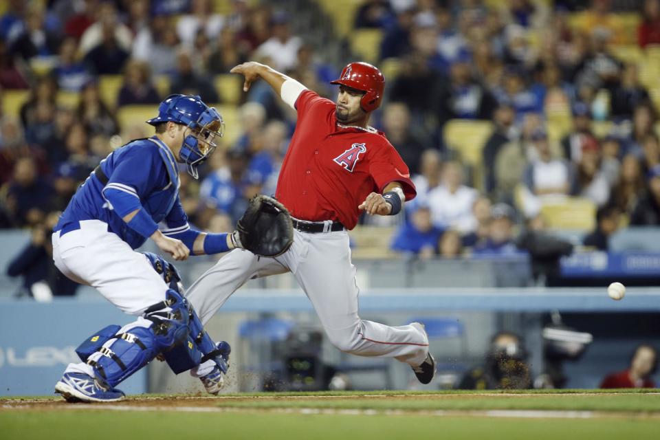 Los Angeles Angels' Albert Pujols scores behind Los Angeles Dodgers catcher A.J. Ellis as he waits for the throw on a single by Angels' David Freese during the third inning of an exhibition baseball game in Los Angeles, Friday, March 28, 2014. (AP Photo/Danny Moloshok)