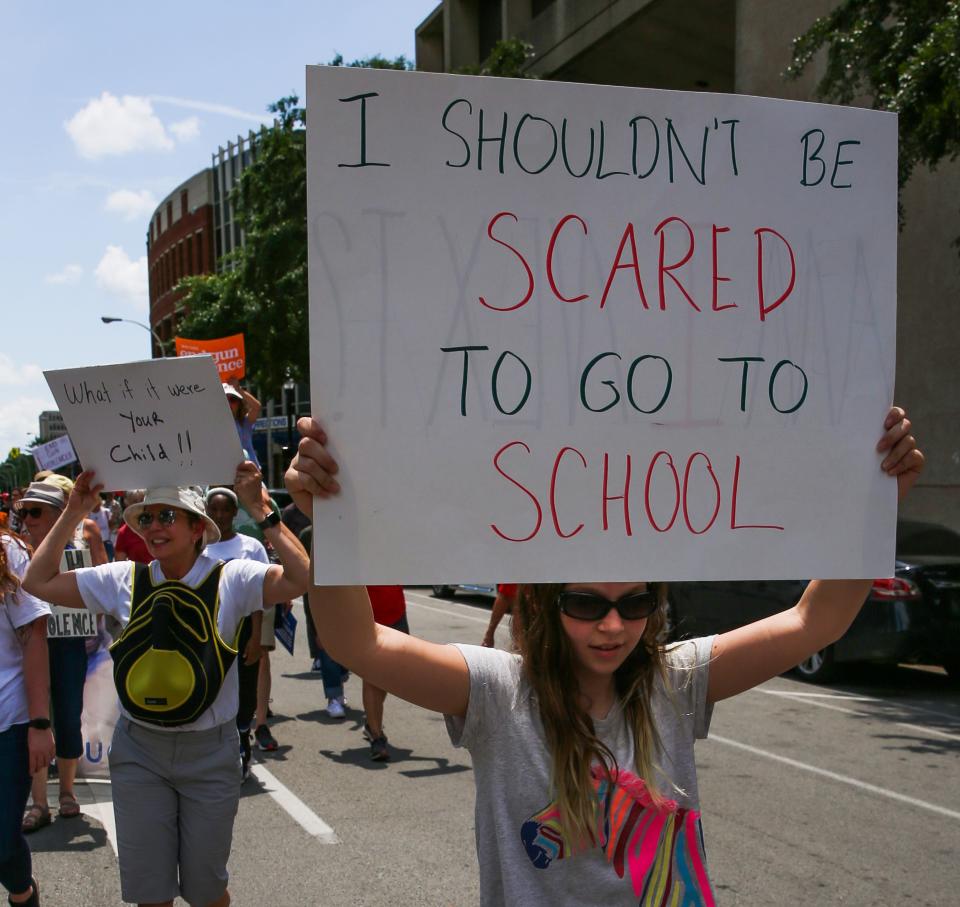 Violet Dailinger, 11, holds up a sign during a march protesting gun violence in downtown Louisville, Kentucky on June 11, 2022. 