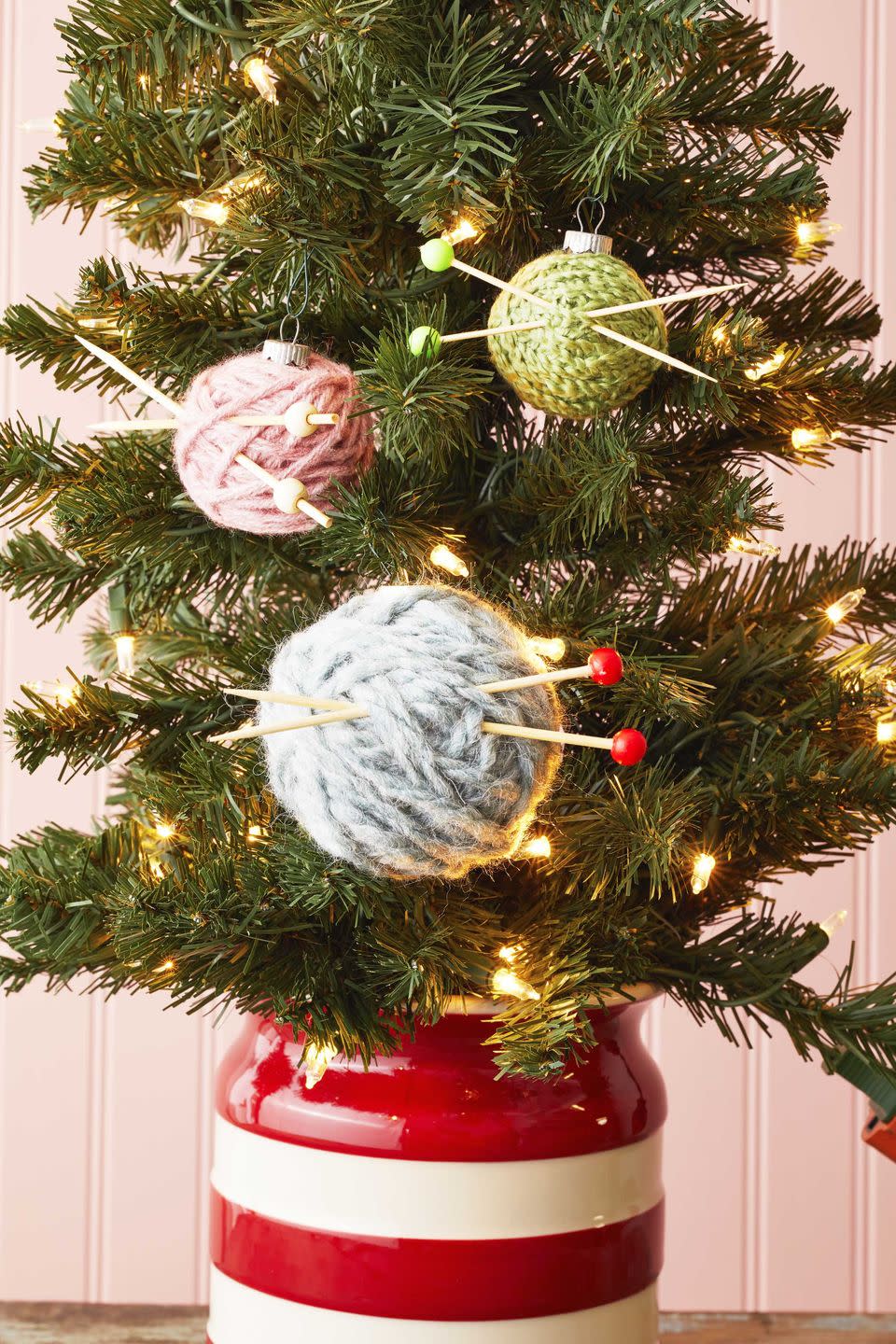 ornaments wrapped with yarn and threaded with cocktail pics meant to look like knitting needles