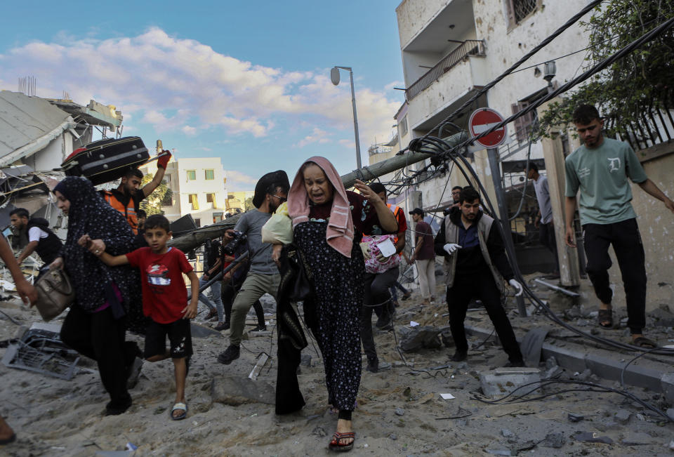 Palestinian families rush out of their homes after Israeli airstrikes targeting their neighbourhood in Gaza City, central Gaza Strip, Tuesday, Oct. 17, 2023. (AP Photo/Abed Khaled)