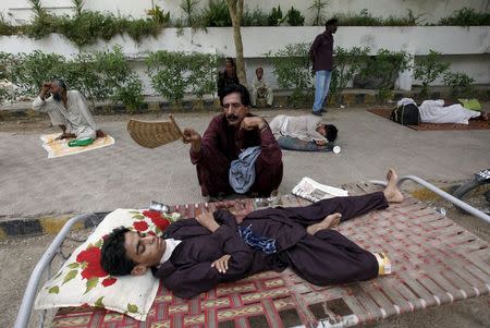 A man uses a hand-held fan to cool down his son, while waiting for their turn for a medical checkup, outside Jinnah Postgraduate Medical Centre (JPMC) during intense hot weather in Karachi, Pakistan, June 23, 2015. REUTERS/Akhtar Soomro