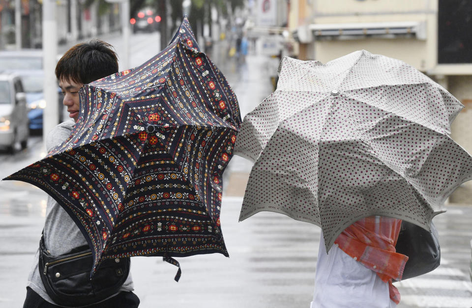 People walk in a strong wind as a typhoon approaches in Naha, Okinawa prefecture, southern Japan Saturday, Sept. 29, 2018. (Ryosuke Uematsu/Kyodo News via AP)