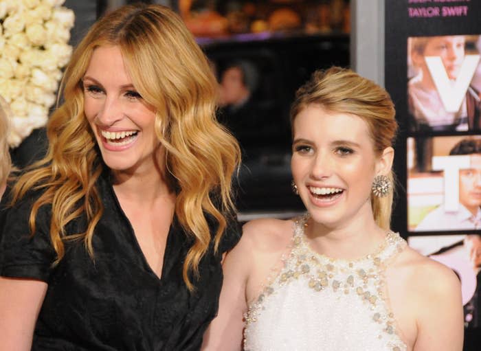 Julia Roberts, in a dark dress, and Emma Roberts, in a embellished halter dress, smiling together at a red carpet event