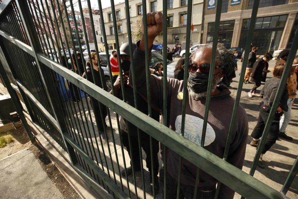 People listen to loudspeakers from outside a fence