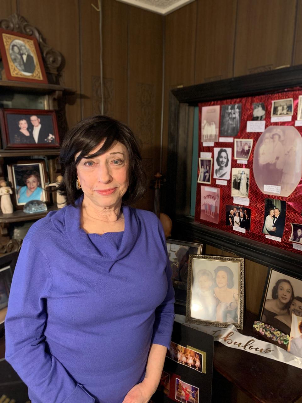 Cynthia Marnik poses beside a collage of photos of her late mother, Georgia Deane, inside Marnik's office at the Deane School of Dance in Mendon, Dec. 6, 2023.