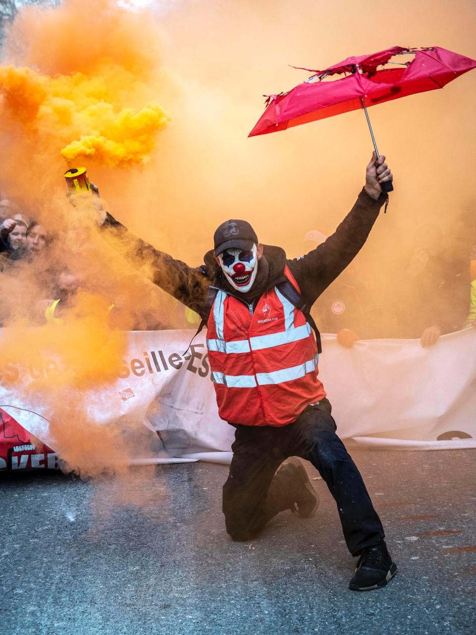 A masked protester holds a smoke grenade as public and private workers demonstrate and shout slogans during a mass strike against pension reforms on December 05, 2019 in Marseille, France.