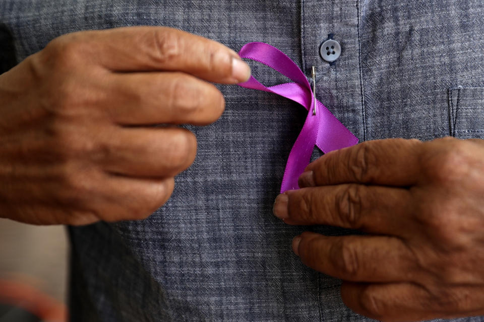 A man puts on a purple ribbon while waiting in line.&nbsp;