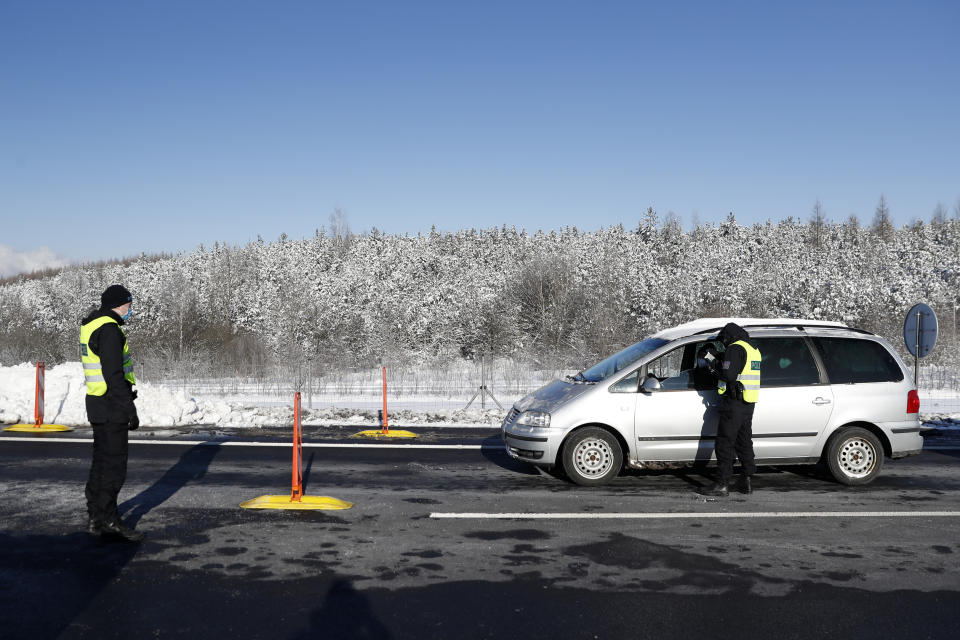 Policemen check documents of a driver near the city of Sokolov, Czech Republic, Friday, Feb. 12, 2021. Almost 600 police officers were deployed to enforce a complete lockdown of the three hardest-hit counties on the border with Germany and Poland to help contain a fast-spreading variant of the coronavirus found in Britain. (AP Photo/Petr David Josek)