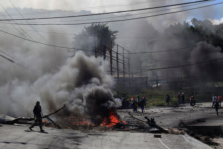 A supporter of Salvador Nasralla, presidential candidate for the Opposition Alliance Against the Dictatorship, walks by a burning barricade settled to block road during a protest caused by the delayed vote count for the presidential election in Tegucigalpa, Honduras December 1, 2017. REUTERS/Jorge Cabrera