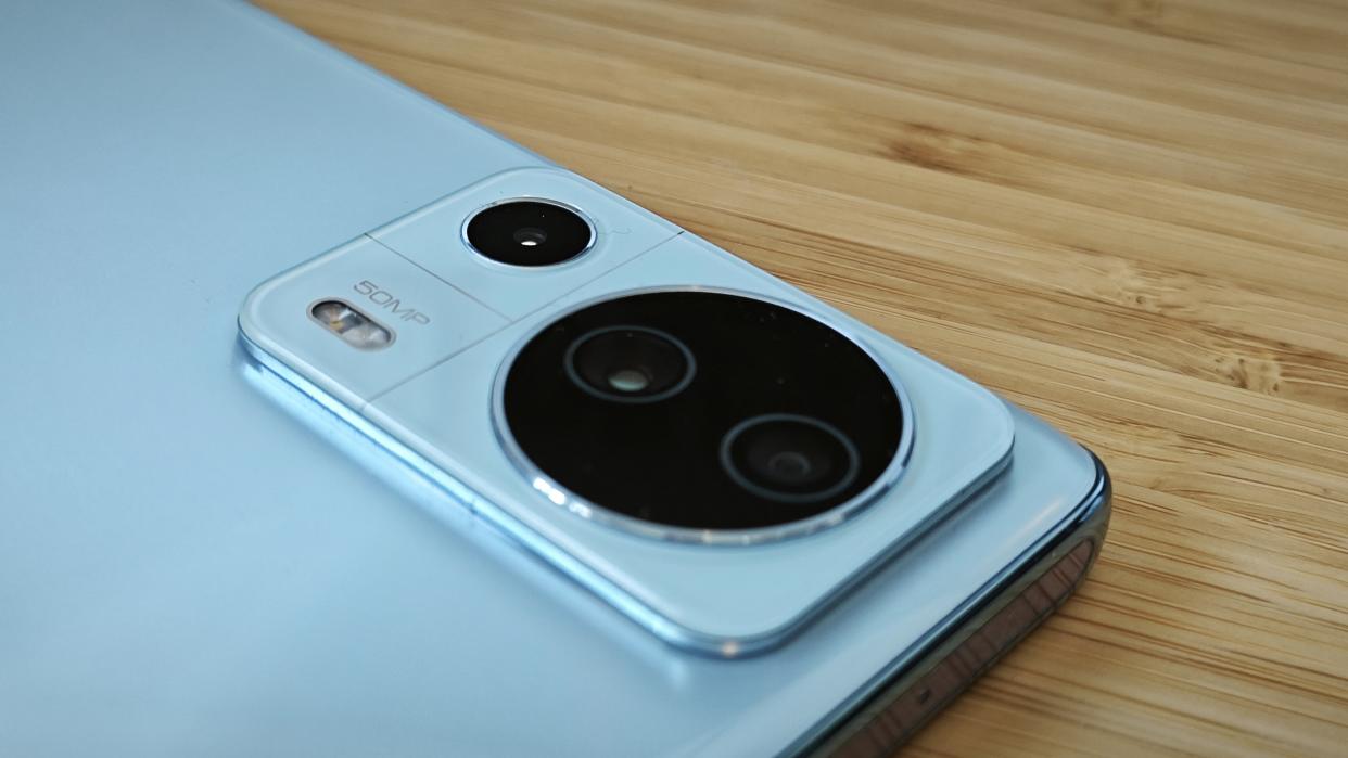  A light-blue Xiaomi 13 Lite camera phone sitting on a wooden desk 