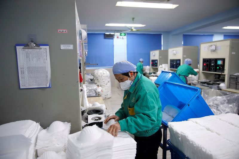 Workers are seen on a production line manufacturing masks at a factory in Shanghai