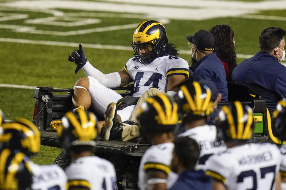 Michigan's Cameron McGrone (44) gestures to teammates as he is carted off the field after being injured during the first half of the team's NCAA college football game against Rutgers on Saturday, Nov. 21, 2020, in Piscataway, N.J. (AP Photo/Frank Franklin II)