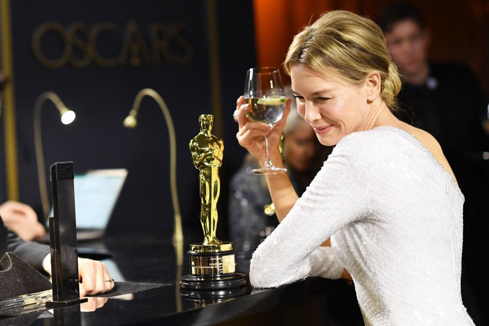 Renée Zellweger stares adoringly at her Best Actress award as she watches it get engraved at the Governors Ball.