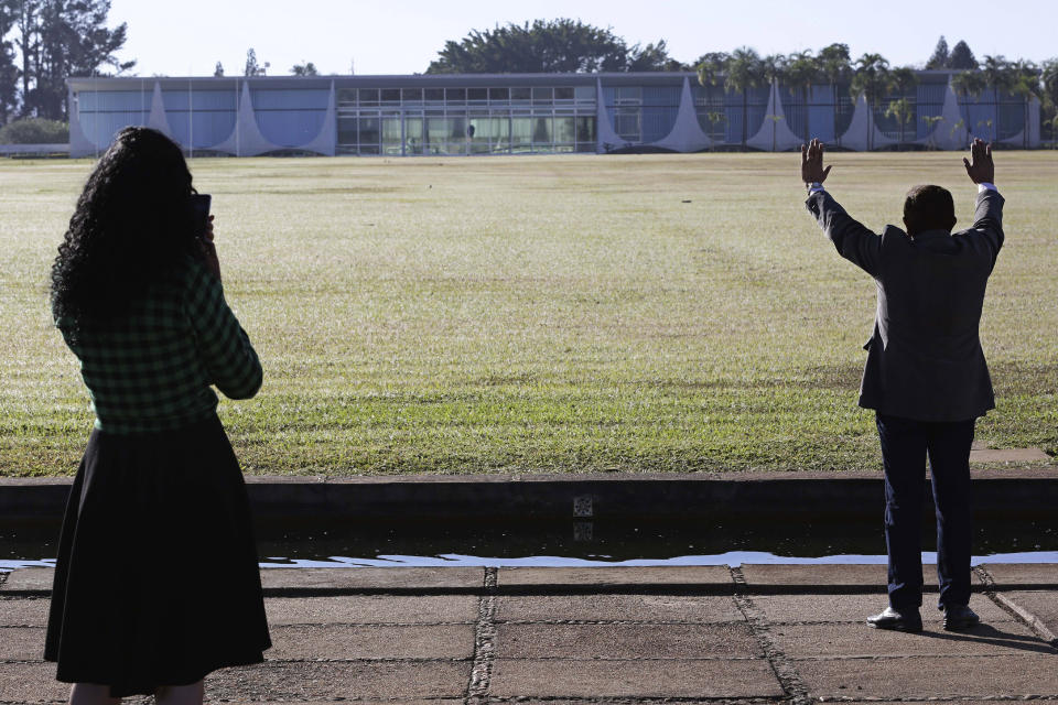 FILE - In this July 7, 2020 file photo, an evangelical pastor prays for Brazil's President Jair Bolsonaro, who said he tested positive for COVID-19, as a fellow evangelical stands with him outside the presidential residence Alvorada Palace in Brasilia, Brazil. Bolsonaro was not chastened by his own bout with COVID-19, and he kept touting hydroxychloroquine long after virtually all others ceased doing so. (AP Photo/Eraldo Peres, File)