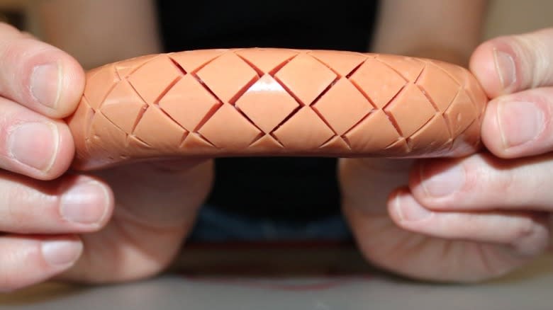 Hands holding crosshatched hot dog