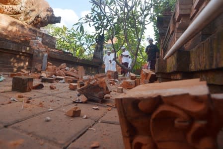 Balinese Hindu men look at a Hindu temple damaged following an earthquake in Denpasar