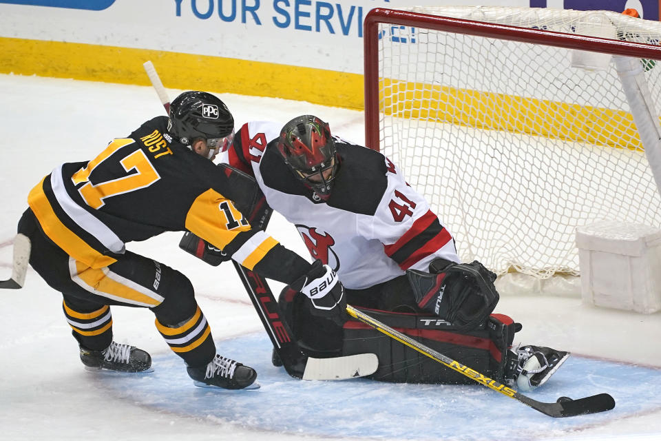 Pittsburgh Penguins Bryan Rust, left, gets the puck around New Jersey Devils goaltender Scott Wedgewood, right, for a goal during the first period of an NHL hockey game in Pittsburgh, Tuesday, April 20, 2021. (AP Photo/Gene J. Puskar)