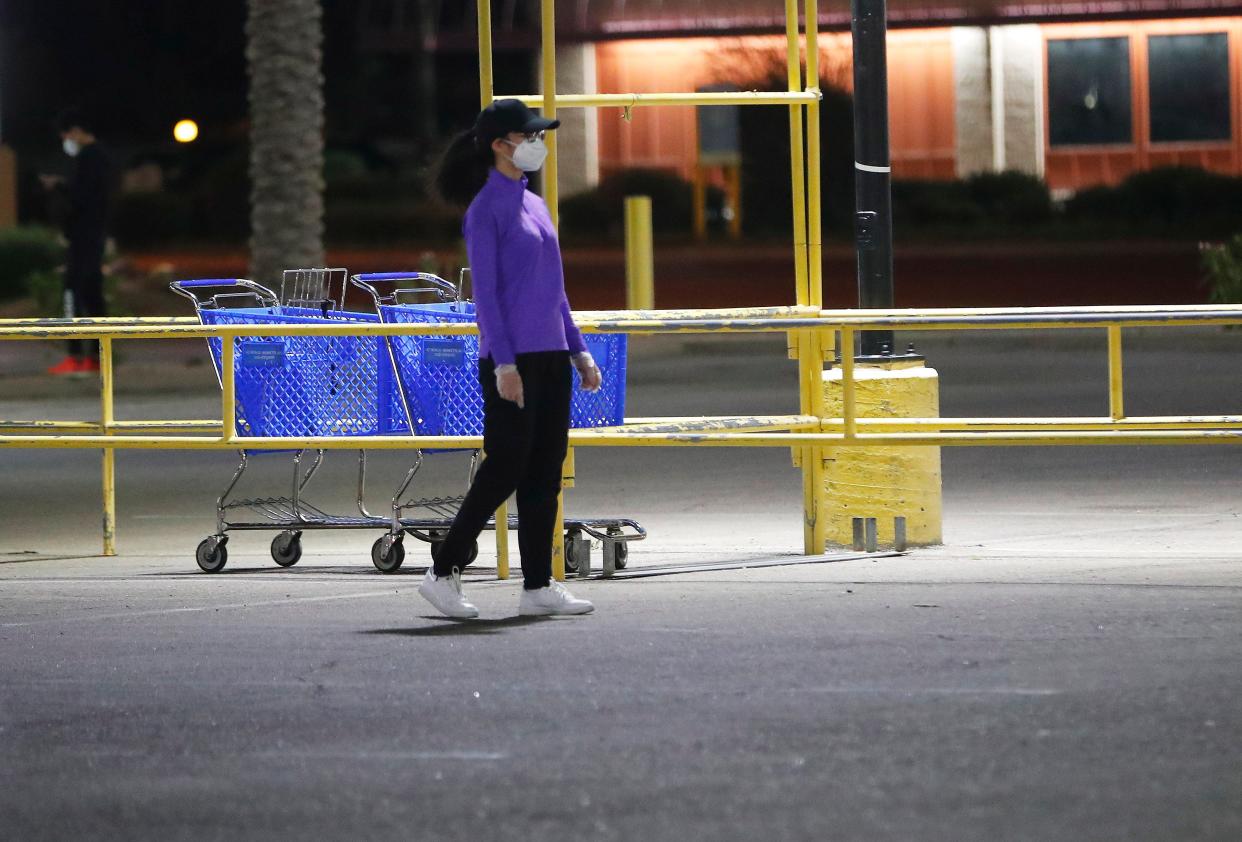 A woman wears gloves and a mask while grocery shopping in Mesa, Ariz. March 29, 2020. Shoppers have been using masks and gloves to protect themselves from COVID-19.