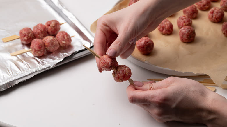 placing meatballs on a skewer
