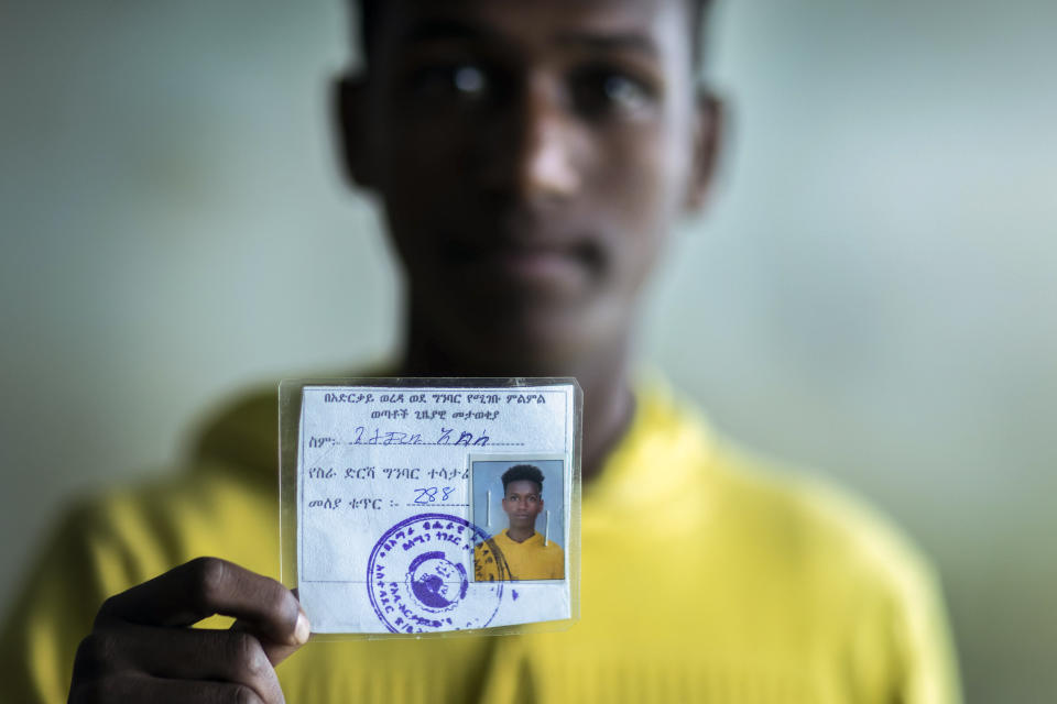 Getachew Abebe, 20 years old, holds his temporary identity card indicating he has chosen to participate at the front line of the conflict, at a center for the internally-displaced in Debark, in the Amhara region of northern Ethiopia Friday, Aug. 27, 2021. Abebe fled his hometown of Addi Arkay when Tigrayan fighters took it over and he is now finalizing basic training so that he can fight with the Fano Youth Liberation Movement militia. (AP Photo/Mulugeta Ayene)