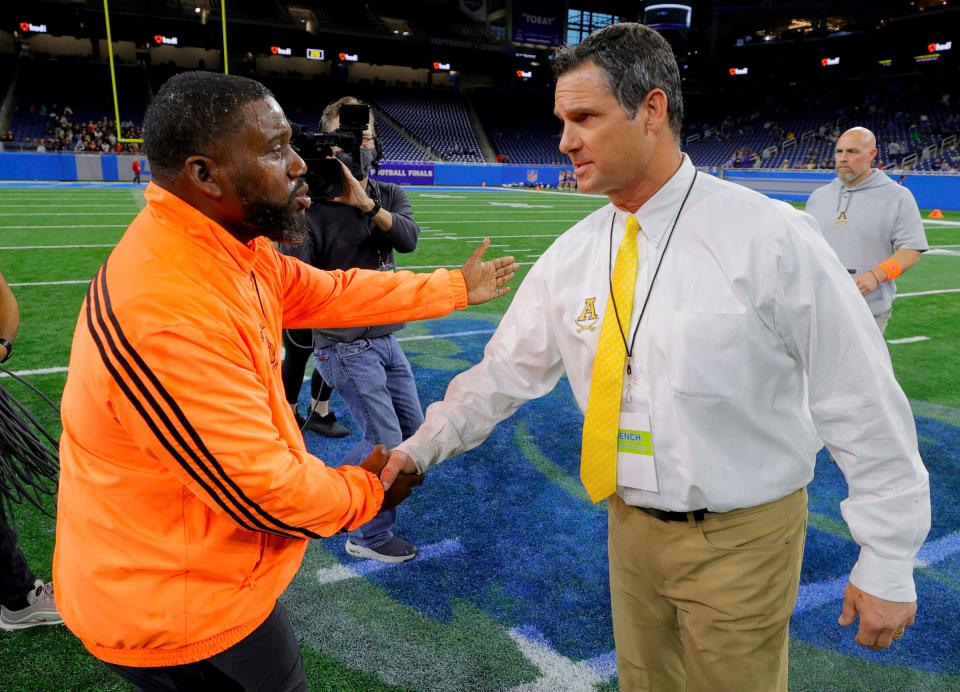 Belleville coach Jermain Crowell, left, and Rochester Adams coach Tony Patritto shake hands at midfield after Belleville's 55-33 win over Rochester Adams in the Division 1 football state final on Saturday Nov, 27, 2021, at Ford Field.