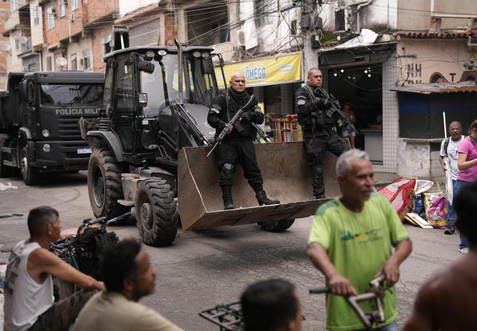 FILE - Police ride in the scoop of a bulldozer as they work to clear street barricades during a security operation against organized crime in the Mare favela, where slain councilwoman Marielle Franco grew up, in Rio de Janeiro, Brazil, Oct. 9, 2023. (AP Photo/Silvia Izquierdo, File)