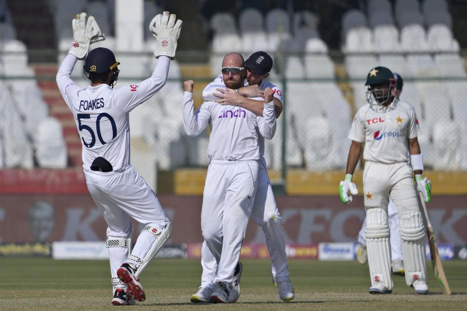 England's Jack Leach, center, celebrates with teammates after taking the wicket of Pakistan's Abdullah Shafique during the third day of third test cricket match between England and Pakistan, in Karachi, Pakistan, Monday, Dec. 19, 2022. (AP Photo/Fareed Khan)
