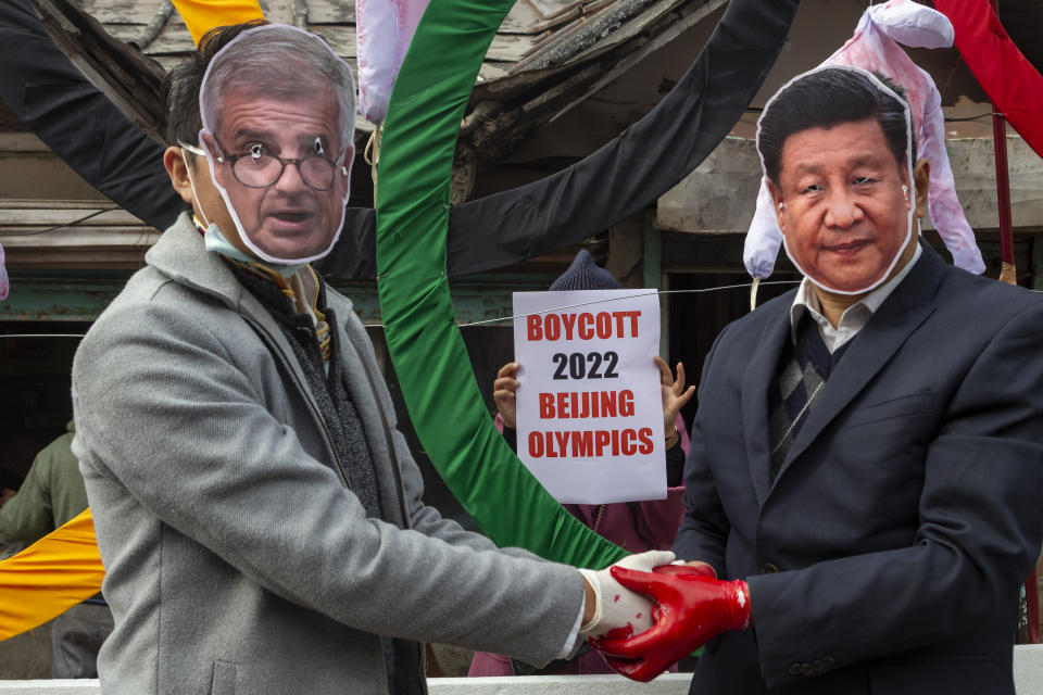 FILE - In this Feb. 3, 2021, file photo, activists wearing masks of the IOC President Thomas Bach and Chinese President Xi Jinping pose in front of the Olympic Rings during a street protest against the holding of the 2022 Winter Olympics in Beijing, in Dharmsala, India. The IOC has declined several recent requests to move the Olympics out of Beijing. (AP Photo/Ashwini Bhatia, File)