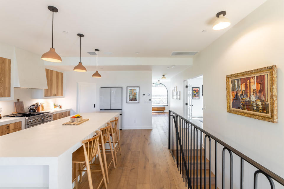 A modern open plan kitchen with wooden floors and white countertops