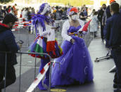 Geert van den Berg, right, queues to attend the show in a purple dress and white wig accessorized with a red feather with his partner Roberto, left, ahead of the first semifinal of the Eurovision Song Contest at Ahoy arena in Rotterdam, Netherlands, Tuesday, May 18, 2021. The competition featuring 39 national songs from nations across Europe as well as Australia and Israel is one of the largest events staged in Europe since the global pandemic began and comes as the continent begins to tentatively ease coronavirus lockdown measures. A crowd of 3,500, tested ahead of time, will be allowed into the Ahoy arena. The number represents a fraction of its capacity to watch the performances live. (AP Photo/Peter Dejong)