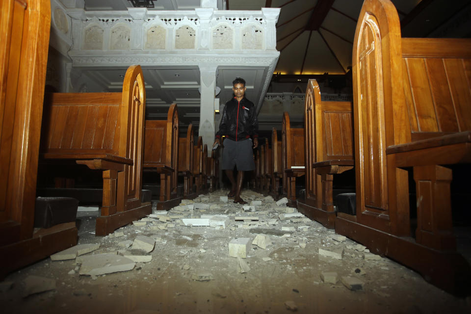 Un hombre camina al interior de una catedral en donde ha caído escombro tras un sismo en Bali, Indonesia, el domingo 5 de agosto de 2018. (AP Foto/Firdia Lisnawati)