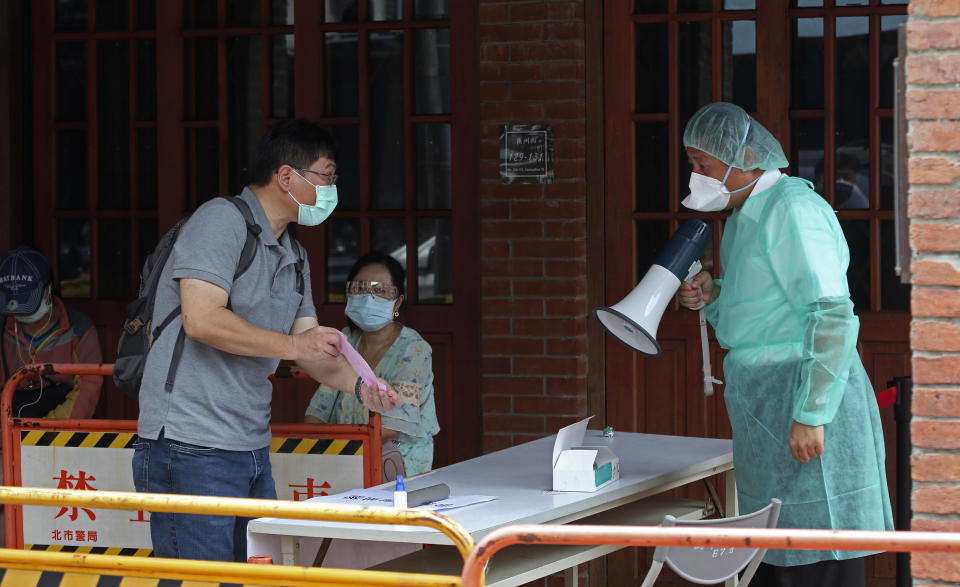 Medical personnel wearing protective gear, guide people at a rapid coronavirus testing center after the infection alert rose to level 3 in Taipei, Taiwan, Tuesday, May 18, 2021. (AP Photo/Chiang Ying-ying)