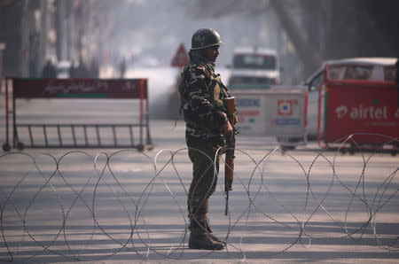 An Indian policeman stands guard behind concertina wire laid across a road leading to the Indian army headquarters in Srinagar December 17, 2018. REUTERS/Danish Ismail
