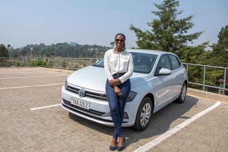 Rwandan Joseline Iradukunda poses next to her "Move" app-driven ride-hailing service Volkswagen Polo in Kigali
