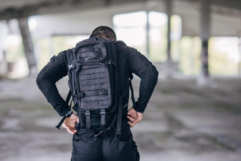 A man putting on a weighted backpack for a rucking workout