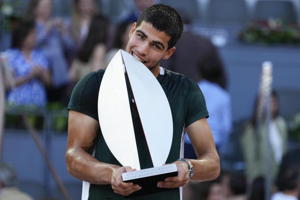 FILE - Carlos Alcaraz, of Spain, bites the trophy after winning the final match against Alexander Zverev, of Germany, at the Mutua Madrid Open tennis tournament in Madrid, Spain, Sunday, May 8, 2022. Alcaraz is a 19-year-old from Spain who is the talk of tennis right now, in part because he just beat Rafael Nadal and Novak Djokovic in consecutive matches on clay on the way to the Madrid Open title. (AP Photo/Paul White, File)