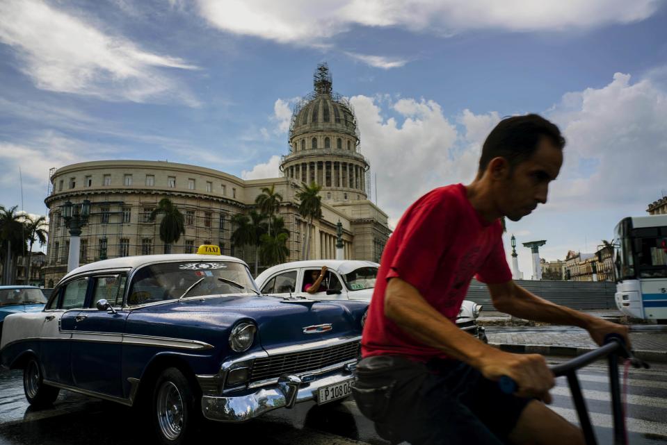 ARCHIVO - En esta foto del 15 de julio de 2016, un hombre va en su bicicleta por una calle de La Habana, cerca del Capitolio, en Cuba. Una encuesta de opinión pública cubana difundida el 21 de marzo de 2017 muestra que la mayoría de los ciudadanos isleños aprueban la normalización de relaciones con EEUU y una amplia mayoría quiere que vayan más turistas y se amplíe la propiedad privada de negocios. (AP Foto/Ramón Espinosa, File)