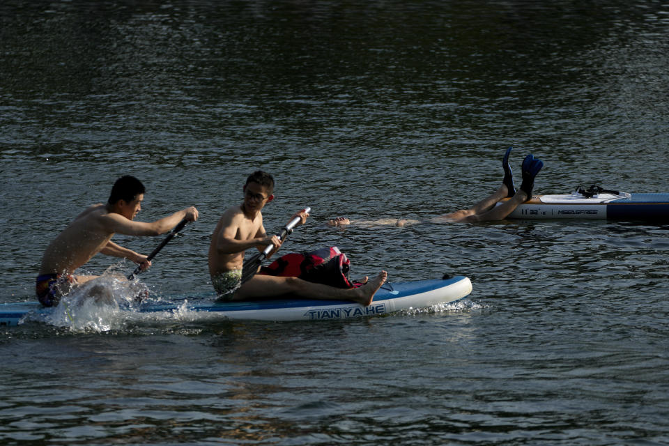 Residents cool off in a lake from an unseasonably hot day in Beijing, Sunday, June 16, 2024. China is being buffeted by two weather extremes, with heavy rain and flooding in parts of the south and a heat wave and potential drought in the north. (AP Photo/Andy Wong)