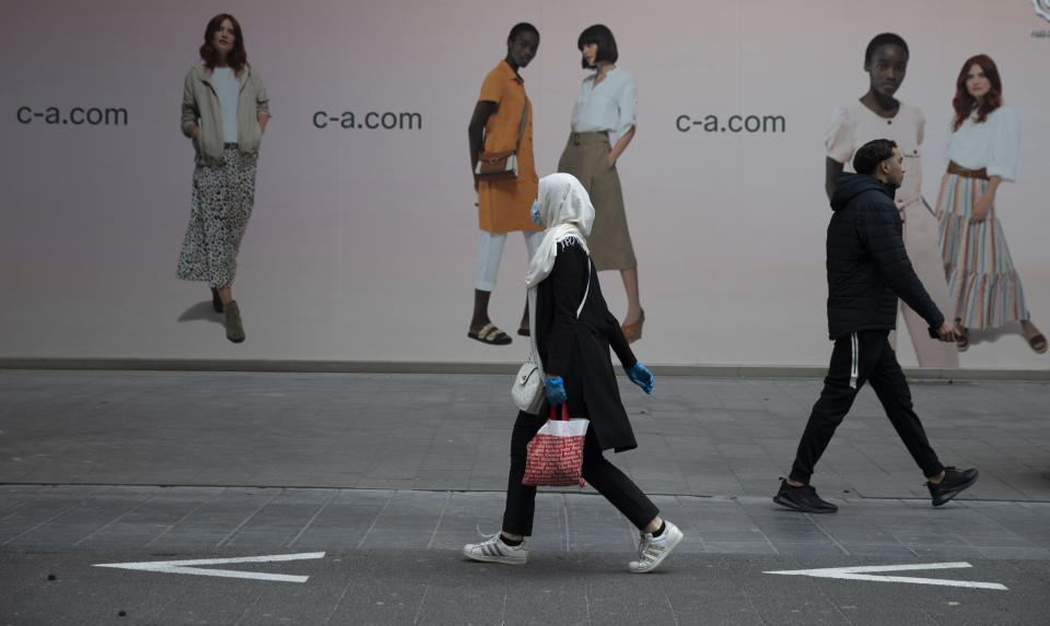 FILE - In this Monday, May 11, 2020 file photo, a woman and man walk past each other on a main shopping street in Antwerp, Belgium. The European Union executive announced Thursday, March 4, 2021 that it wants to force employers to be much more open about how much money staff makes to make it easier for women to challenge wage imbalances and further closer the gender pay gap. The EU made it clear that women workers had been disproportionally affected by the pandemic, many having to add more home tasks to their work schedule because of closure of schools and day care centers. (AP Photo/Virginia Mayo, File)