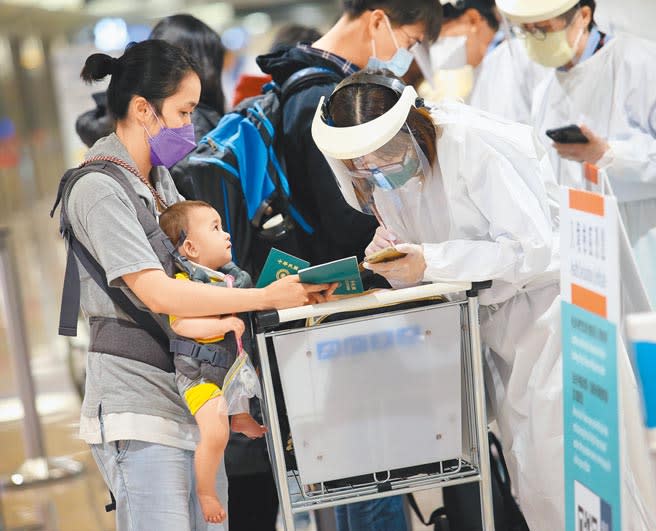 在桃園機場入境管制區內，防疫人員協助旅客完成入境檢疫憑證。（范揚光攝）