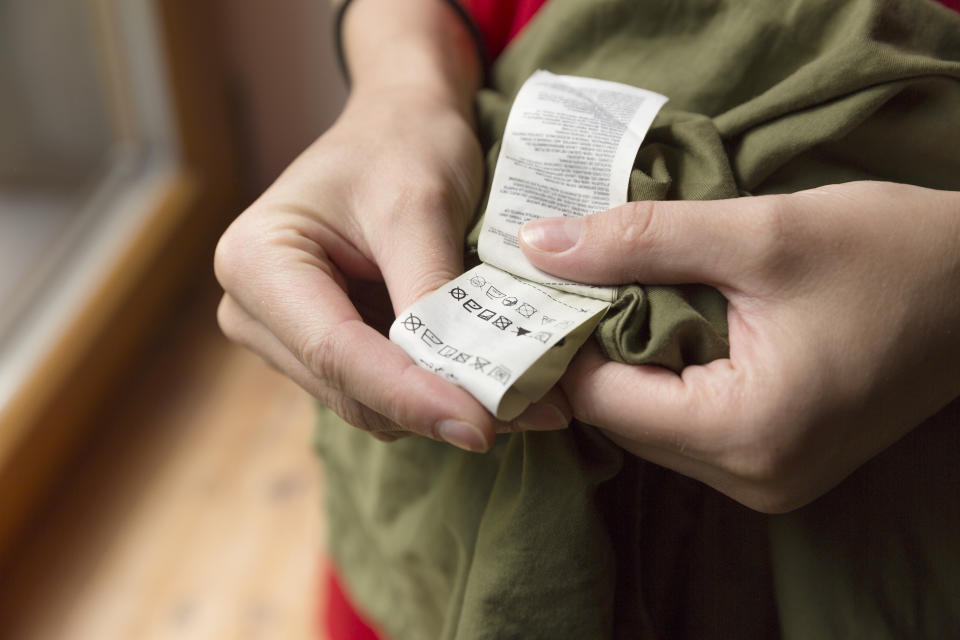 Close-up of person reading the clothing label showing washing instructions