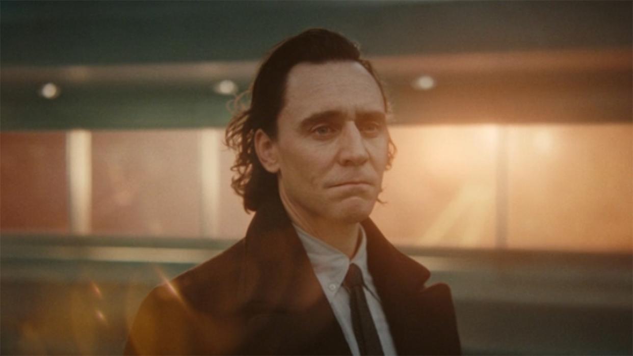  Image from the Marvel T.V. show Loki, season 2 episode 6. Close up of a man with dark slicked back hair who looks sad but determinedly into the distance. He is wearing a dark jacket, light shirt and black tie. 