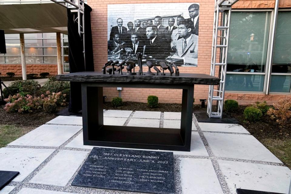 A sculpture commemorating the 1967 Cleveland summit with Muhammad Ali, Jim Brown and others is unveiled Wednesday, Oct. 11, 2023, in Cleveland. The sculpture is a representation of the press conference table where the Black athletes sat; at photo of the event is at rear. (AP Photo/Sue Ogrocki)