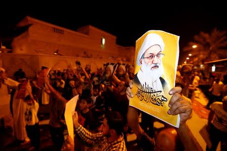 Protesters holding photos of Bahrain's leading Shi'ite cleric Isa Qassim shout religious slogans during a sit-in outside his home in the village of Diraz west of Manama, Bahrain July 27, 2016. Qassim went on trial on Wednesday on charges of collecting donations illegally and money laundering. REUTERS/Hamad I Mohammed