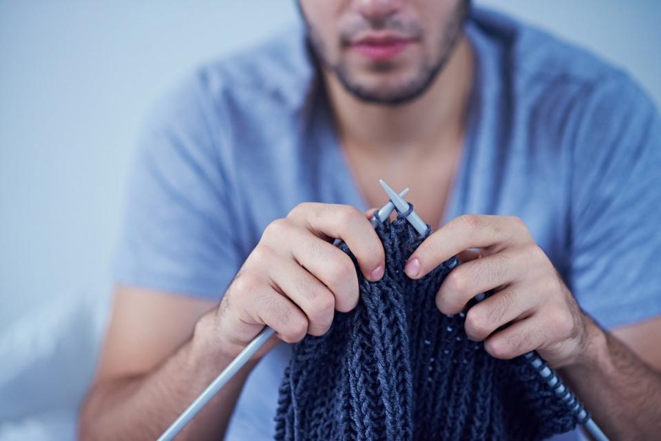 A person knitting a throw blanket for the home.