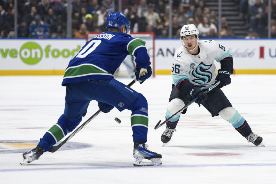 Seattle Kraken's Kailer Yamamoto (56) passes the puck past Vancouver Canucks' Elias Pettersson (40) during the third period of an NHL hockey game Saturday, Nov. 18, 2023, in Vancouver, British Columbia. (Ethan Cairns/The Canadian Press via AP)