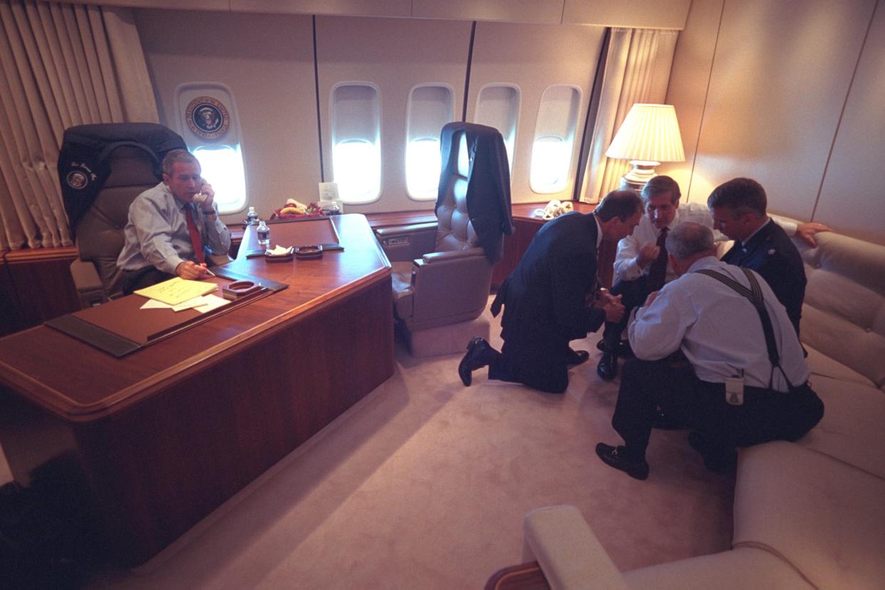George W. Bush talks on the phone and staffers huddle aboard Air Force One.