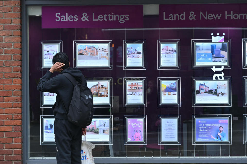 A member of the public looks at houses for sale listed on a real estate agency. (Credit: Justin Tallis, AFP via Getty Images)